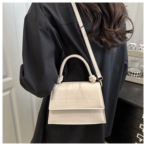 Detail of cream faux crocodile texture handbag with unique knotted handle and strap