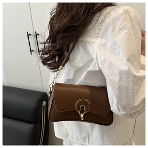 Detail of dark brown leather shoulder bag with gold ring buckle and chain strap