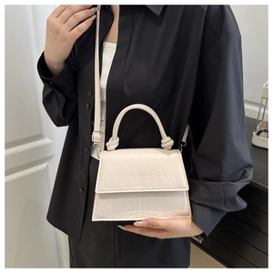 Close-up of cream square bag showing crocodile pattern texture and knotted handle detail