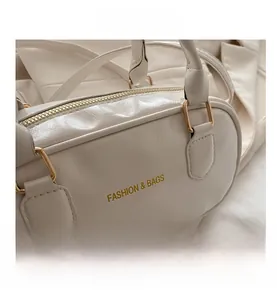 Detail of off-white pleated PU leather bag with gold hardware and embossed lettering