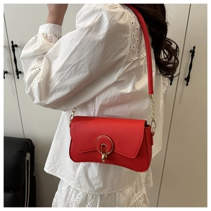 Detail of red crescent-shaped crossbody bag with gold ring buckle and chain strap