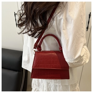 Detail of red crocodile embossed leather texture on a stylish luxury top handle bag