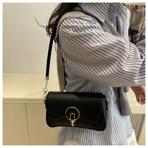 Detail of elegant black square bag with gold metal buckle and leather chain strap