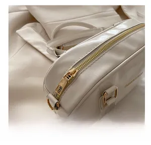 Detail of glossy white handbag featuring a smooth gold zipper and fashion text logo
