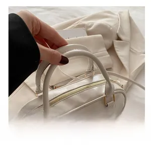 Close-up of comfortable handles and gold metal hardware on off-white Boston handbag