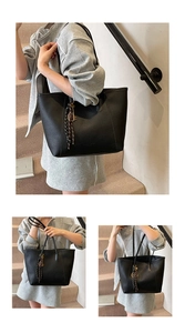 Detail of black pebbled leather tote bag with woven tassel and keyring for daily commute