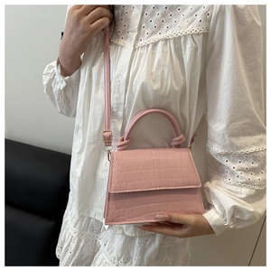 Close-up of pink faux crocodile leather texture and handle on a mini handbag