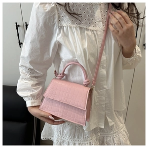 Detail of pink croc-embossed mini handbag with knotted handle and detachable strap
