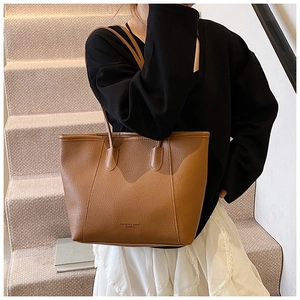 Detail of brown lychee grain leather bucket bag featuring fashion logo on the bottom