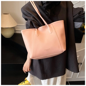 Macro detail of pink lychee grain leather tote bag with elegant handles and lettering