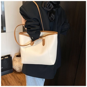 Detail of cream-colored pebble leather bucket bag with contrasting dark brown shoulder strap