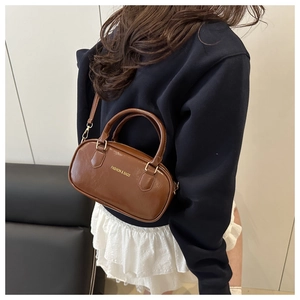 Detail view of a vintage brown mini Boston bag featuring golden hardware and leather texture
