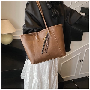 Detail view of brown pebbled leather tote bag with silk scarf and fashion text print