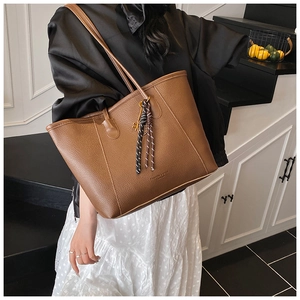 Close-up of brown litchi pattern leather bucket bag with tassel and gold hardware