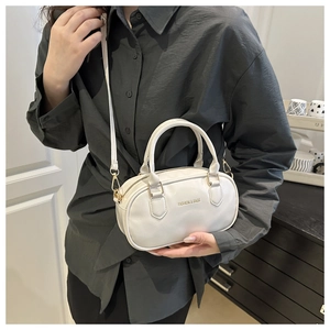 Vista dettagliata di una borsa a cuscino in pelle bianca con zip dorata e testo moda