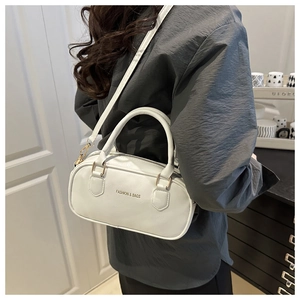 Cream leather pillow bag shown on model with adjustable strap and golden fashion text
