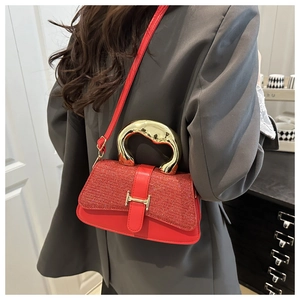 Detail der roten Ledertasche mit goldener H-Schnalle und Metallgriff am Modell