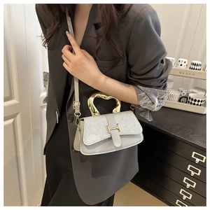 Detail of grey crossbody bag featuring a gold heart metal handle and H-shaped buckle