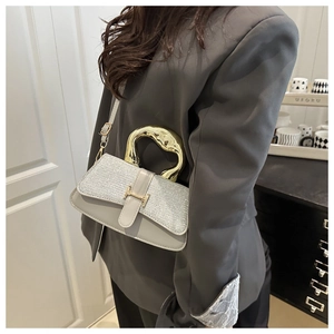 Close-up of a luxury leather handbag featuring a unique curved metal handle and H buckle