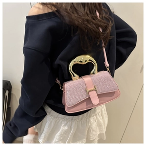 Detail of pink rhinestone handbag with gold H-buckle and artistic metal handle