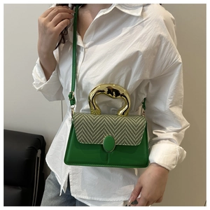 Detail of green handbag showing woven pattern texture and irregular gold metal handle