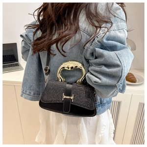 Close-up of black sequined handbag featuring a gold artistic handle and H-buckle detail