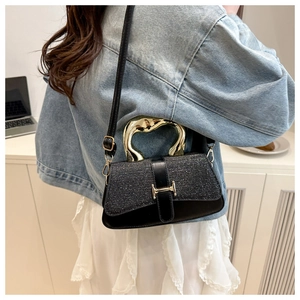 Close-up of black sequin and leather crossbody bag with wave-shaped gold metal handle