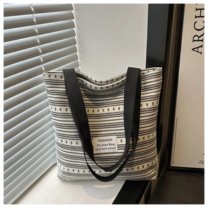 Close-up of black and white striped knit fabric and FASHION label on canvas tote bag