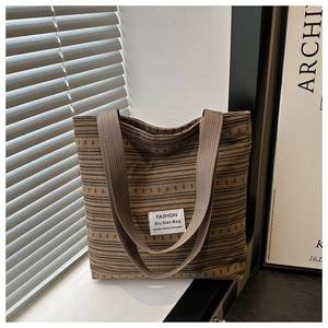 Detail of canvas tote bag with brown stripes and fashion label on a window sill