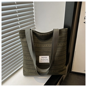Close-up of olive green canvas tote bag showing striped fabric texture and fashion label