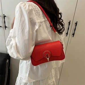 Chic red faux leather box handbag with gold chain strap shown on a white dress