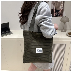 Détail du sac cabas rayé vert foncé avec large bandoulière grise et étiquette tissée