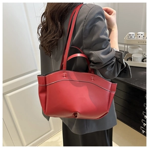 Detail of red leather tote bag with white contrast stitching and dual handle design