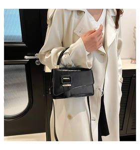 Detail view of the black leather handbag featuring a gold buckle and round handle