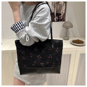Detail of cherry print corduroy tote bag showing smooth leather bottom and strap