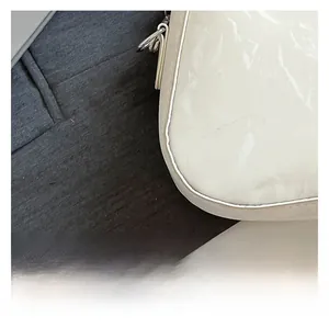 Macro shot of white glossy pleated texture on a stylish underarm bag with patent leather finish