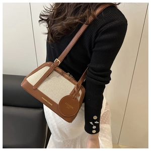 Detail view of brown leather and beige canvas crossbody bag worn by a model
