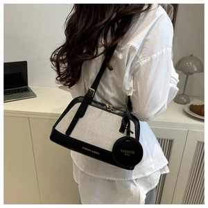 Detail showing the contrast canvas and black leather trim of the commuter shoulder bag