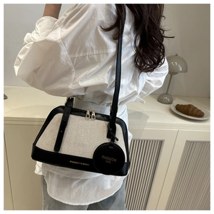 Detail view of canvas and black leather crossbody bag with a circular fashion charm