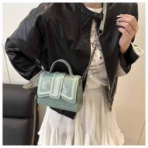 Close-up of mint green crocodile pattern handbag with chain strap on a stylish model