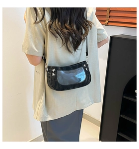 Detail of black crossbody bag with star rivets and clear window on a person shoulder
