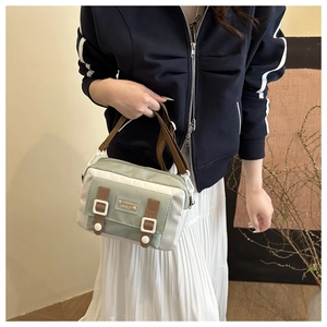 Detail van vintage canvas crossbodytas met contrasterend groen paneel en gespen