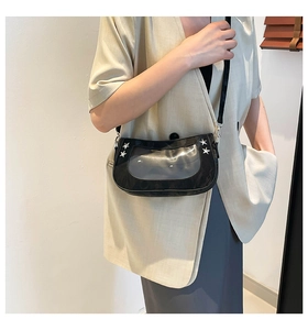 Detail of fashion underarm bag featuring transparent PVC window and silver star rivets