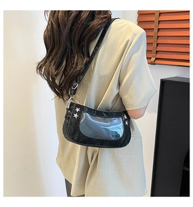 Detail of black glossy underarm bag with transparent crescent window and silver stars