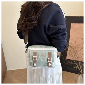 Gedetailleerd beeld van een groen-witte canvas crossbodytas met verstelbare bruine riem