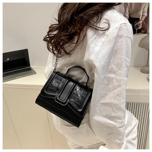 Detail of black crocodile texture bag with chain strap and handle in lifestyle setting