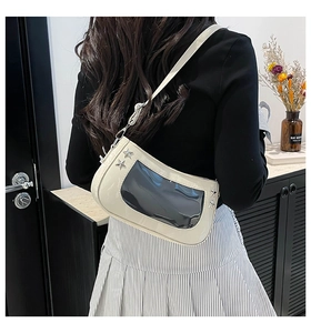 Close-up of beige shoulder bag with transparent PVC window and silver star metal rivets