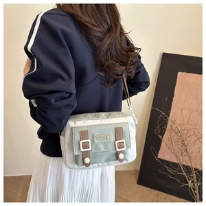 Close-up of mint green and beige fabric crossbody bag with leather strap and buckle details