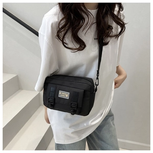 Detail van een zwarte nylon crossbodytas met stijlvolle gespen en een konijnenpatch
