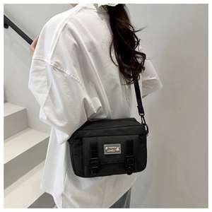 Detail van zwarte nylon crossbodytas met modieus konijn-embleem op een model